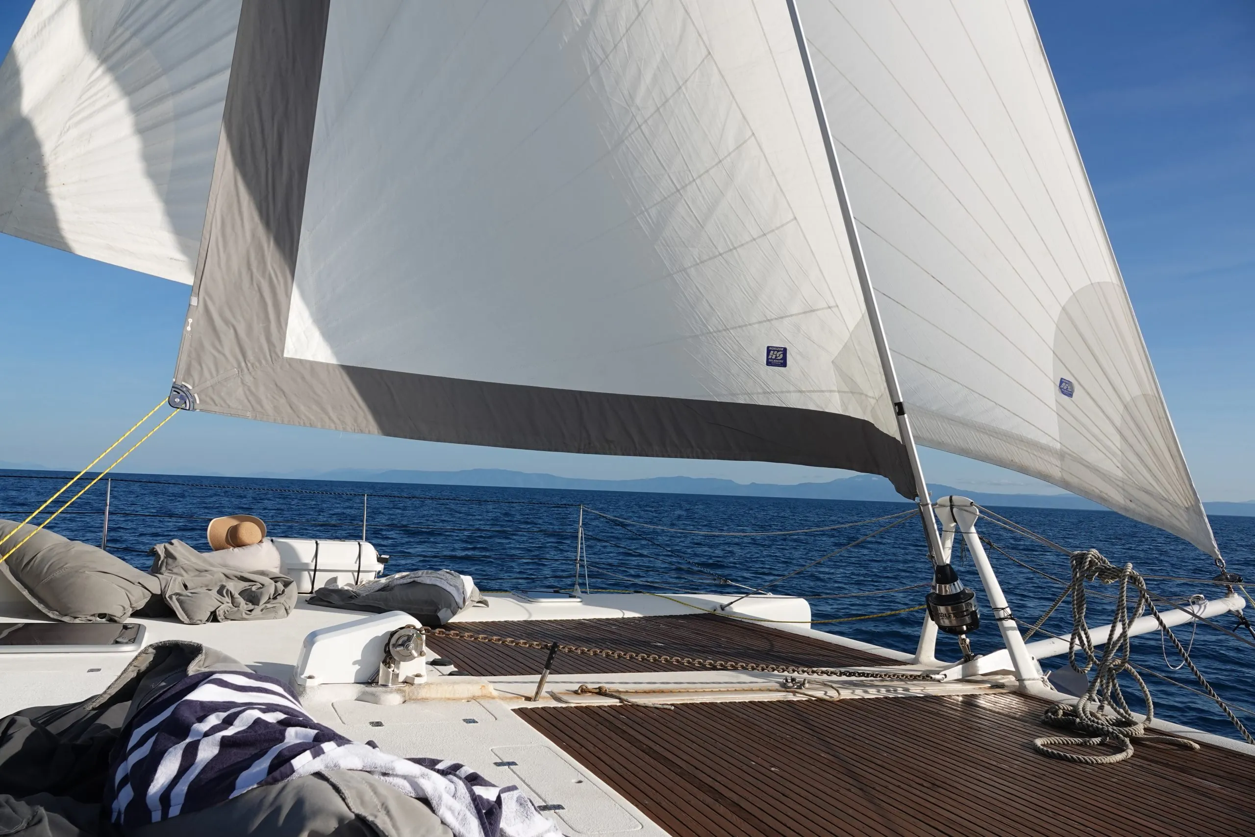 The foredeck of a sailing catamaran under full canvas on the Coral Sea