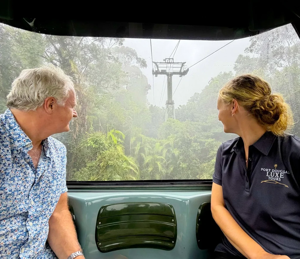 A Port Douglas Luxe Tours guide and a guest in a cableway gondola above the rainforest canopy